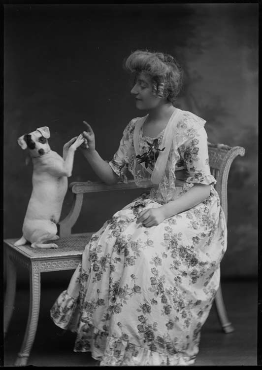 Une femme assise joue avec un chien assis sur ses pattes arrières