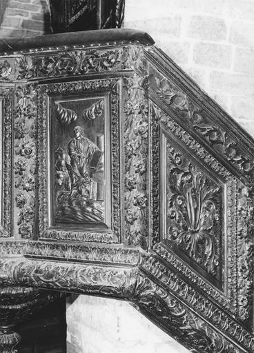 Chaire à prêcher : détail de la partie haute de l'escalier au riche décor de chutes de fleurs, frises de feuilles et rinceaux végétaux, et au panneau sculpté en bas-relief de l'évangéliste saint Luc, bois sculpté ; avant restauration