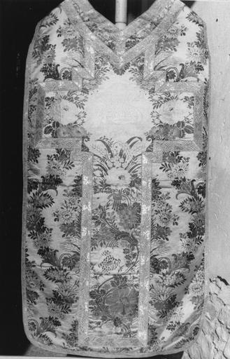 Chasuble à motifs de guirlandes de fleurs sur fond blanc, agrémenté d'une croix formée par un tissu aux bouquets de fleurs encadrant la figure de l'Agneau immolé, délimitée par un galon de fils de métal, soie brochée - © Ministère de la Culture (France), Médiathèque du patrimoine et de la photographie (objets mobiliers), tous droits réservés