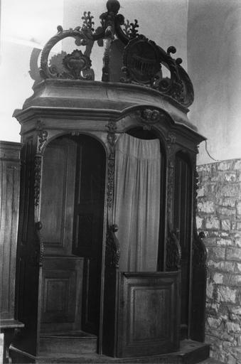 Confessionnal à façade galbée, au décor sculpté de motifs végétaux et de chérubins, surmonté d'un dais formé de volutes et d'un médaillon, bois taillé - © Ministère de la Culture (France), Médiathèque du patrimoine et de la photographie (objets mobiliers), tous droits réservés