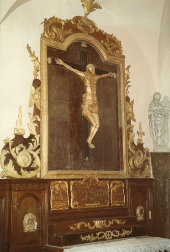Retable, statue : Christ en croix placé dans un cadre en bois sculpté en cadré de volutes végétales, prédelle ornée de trois panneaux sculptés de scènes en bas-relief, bois sculpté, peint, doré - © Ministère de la Culture (France), Médiathèque du patrimoine et de la photographie (objets mobiliers), tous droits réservés