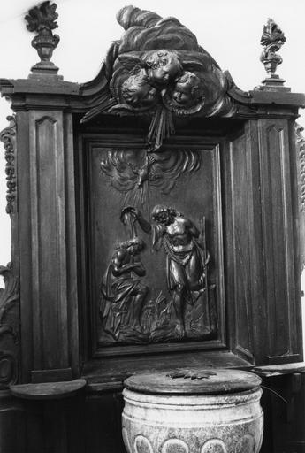 Retable des fonts baptismaux, bas-relief : Le Baptême du Christ, retable architecturé à fronton sculpté de trois chérubins dans des nuées, et encadré de pots à feu, bois sculpté - © Ministère de la Culture (France), Médiathèque du patrimoine et de la photographie (objets mobiliers), tous droits réservés