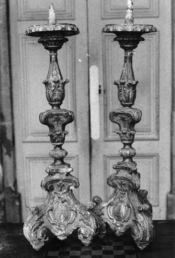 Deux chandeliers d'autel aux pieds tripodes formés par de grosses volutes végétales, et ornés d'armoiries, l'ensemble présente volutes et motifs végétaux, bois sculpté, doré - © Ministère de la Culture (France), Médiathèque du patrimoine et de la photographie (objets mobiliers), tous droits réservés