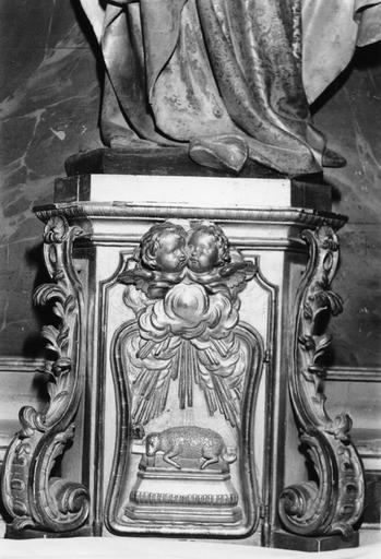 Tabernacle à angles abattus agrémentés de grosses volutes végétales, porte sculptée en relief de l'Agneau immolé sur un autel et de chérubins, bois sculpté, doré