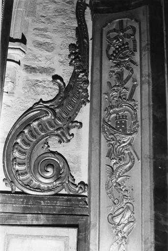 Retable : détail d'un panneau sculpté d'un trophée mêlant cartouche à la tour, motifs végétaux, couronne et sceptre, dragon, vase, bois sculpté, doré