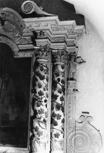 Retable : détail des colonnes torses agrémentées de branches de vigne, flanquées d'une volute et d'un angelot, bois sculpté, peint, doré ; avant restauration