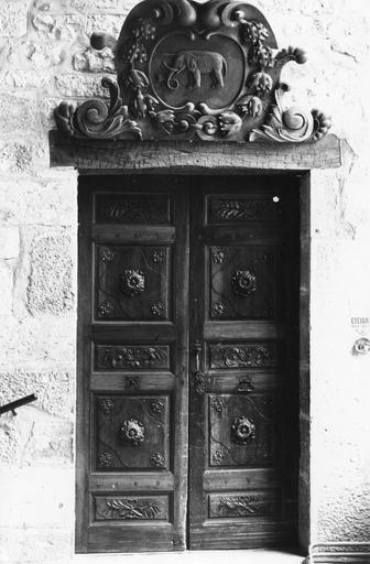 Porte à deux vantaux au décor de motifs quadrilobés, de rosaces, de branches de palmes, le linteau est surmonté d'un gros cartouche sculpté en son centre d'un éléphant, bois taillé