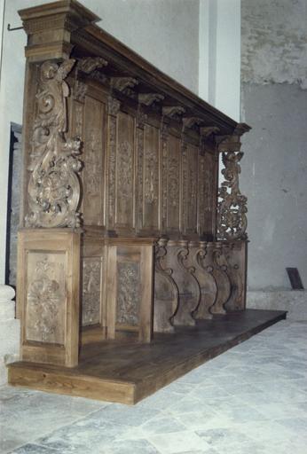 Lambris de revêtement, stalles : panneaux sculptés de bouquets de fleurs ou de volutes végétales, séparés par des pilastres à chutes de feuilles et chapiteaux corinthiens, les extrémités sont sculptées d'un gros rinceau végétal surmonté d'un chérubin, boi