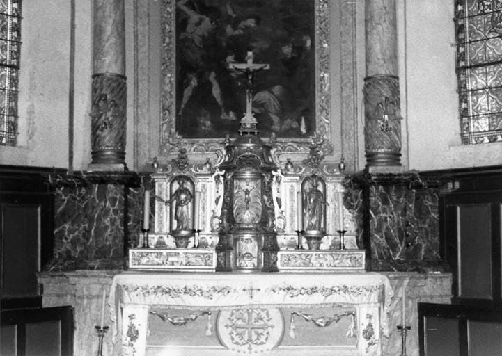 Tabernacle architecturé à trois travées, richement sculpté de volutes et éléments végétaux, agrémenté des statuettes de saint Etienne et d'un saint personnage couronné, un Christ en croix et l'Agneau immolé en relief sur les portes, bois sculpté, doré