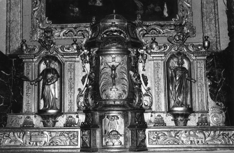 Tabernacle architecturé à trois travées, richement sculpté de volutes et éléments végétaux, agrémenté des statuettes de saint Etienne et d'un saint personnage couronné, un Christ en croix et l'Agneau immolé en relief sur les portes, bois sculpté, doré