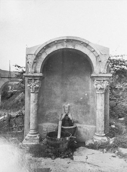 Fontaine publique composée d'un arc et de deux piliers à chapiteaux sculptés issus du cloître