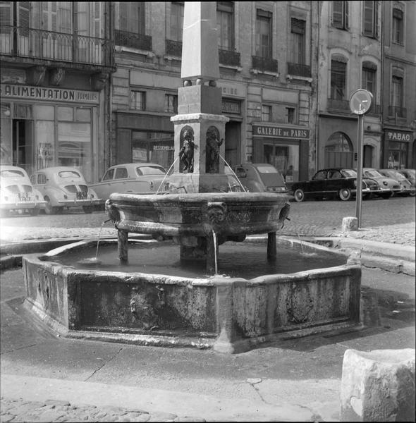 La fontaine et les commerces de la place