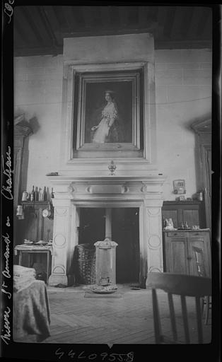 Intérieur, salon transformé en cuisine : poêle à bois installée dans la cheminée, portrait peint de femme au dessus