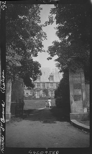 Extérieur, grille du parc ouverte, vue prise vers la façade du château, femme et enfant de dos dans l'allée