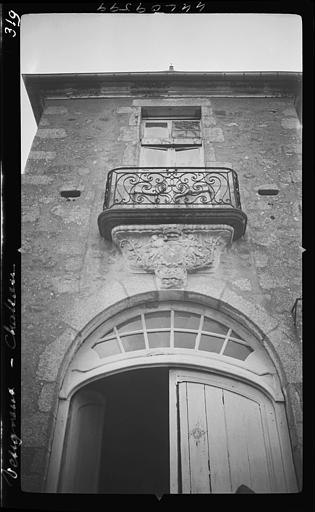 Façade principale, détail : partie supérieure de la porte d'entrée et dessous sculpté (blason) du balcon du premier étage