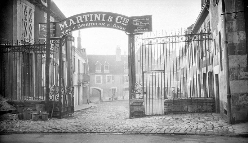 Grille d'entrée, côté rue, à l'enseigne 'Martini et Cie, vins et spiritueux en gros'