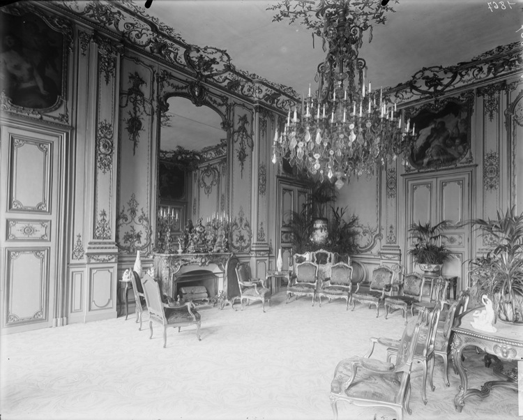 Grand salon de réception : boiseries, tableaux encastrés en dessus-de-porte, cheminée et glace, grand lustre central