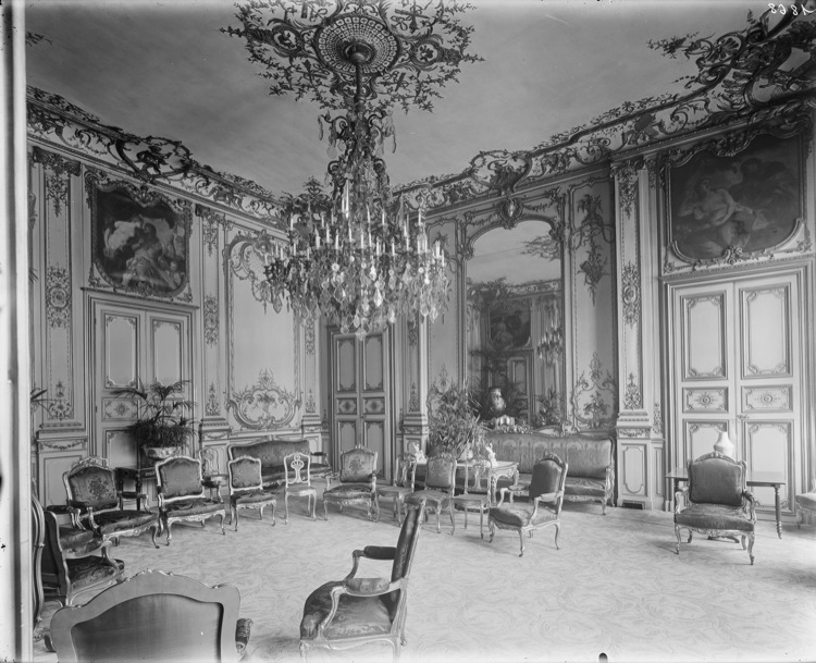 Grand salon de réception : boiseries, tableaux encastrés en dessus-de-porte, glace, grand lustre central