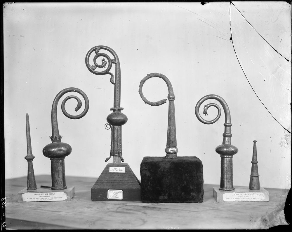 Six éléments de crosses décorés de têtes de dragons : deux crosses abbatiales (2 crosserons et 2 bouterolles) de l'abbaye de Saint-Amand de Rouen encadrent une crosse du musée de Saint-Omer et la crosse pastorale de Pierre d'Arcis