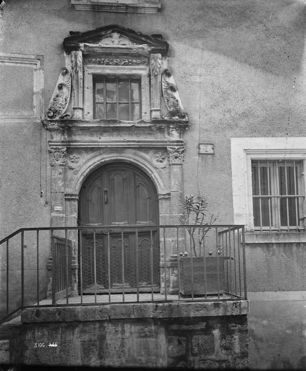 Porte surmontée d'un entablement, d'une fenêtre à fronton et de deux masques sculptés en amortissement