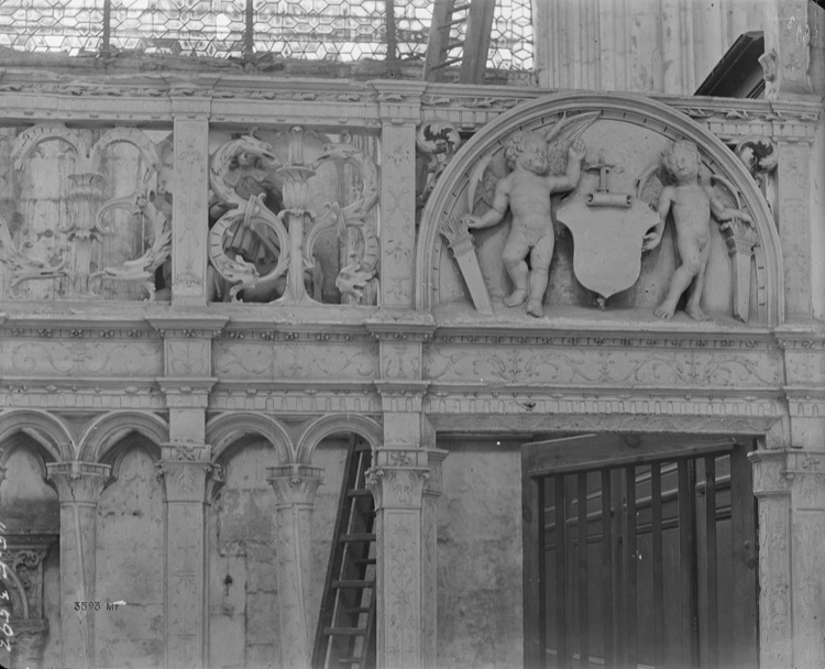 Intérieur, clôture des chapelles latérales et du choeur : frise en partie haute, deux putti ailés de part et d’autre d’un écusson