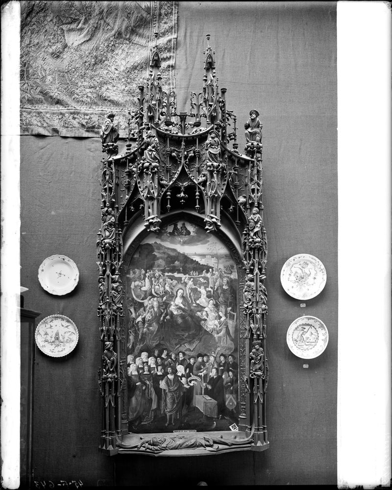 Tableau votif (panneau peint de la confrérie de Notre-Dame du Puy, encadrement en bois sculpté architecturé) : Le Puy dit de 1519 (Glorification de la Vierge), dans la salle d'exposition encadré de quatre assiettes