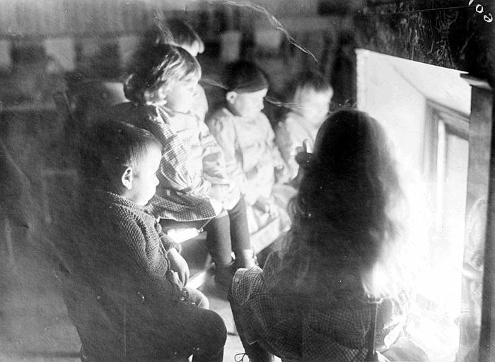 Intérieur, enfants devant une cheminée, photographie prise avant lincendie