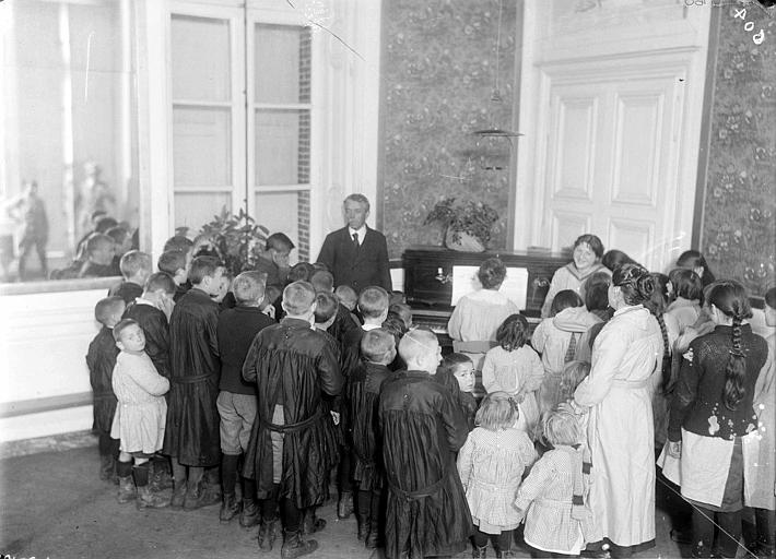 Intérieur : chants à la colonie d'enfants accompagnés par une pianiste, groupe d'enfants et de surveillants