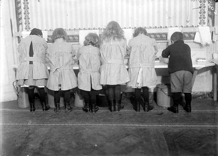 Dortoir des enfants, intérieur : la salle de bains, les enfants de dos se lavent dans des cuvettes