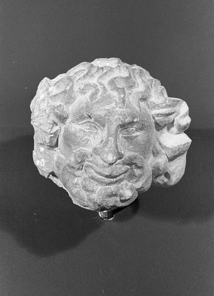 Statue en pierre de Romain, fragment : tête d'homme barbu grimaçant, de face