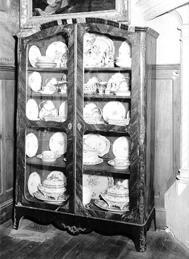 Armoire à portes vitrées Louis XV contenant des pièces de porcelaine, située dans le Grand Salon