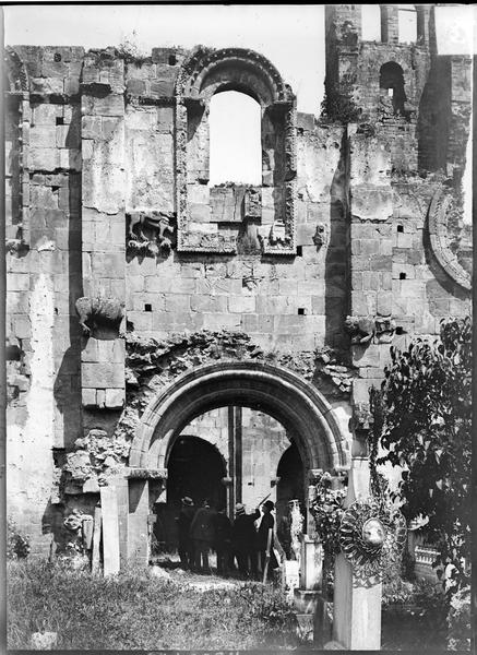 Portail sud et cimetière au premier plan en ruines, touristes