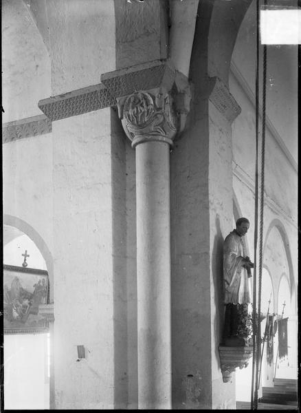 Intérieur : colonne à chapiteau sculpté et statue à la croisée du transept