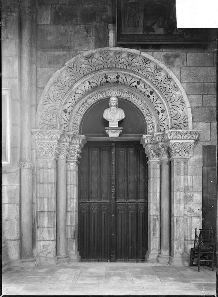 Intérieur : déambulatoire, porte romane surmontée d'un buste du Cardinal de la Luzerne