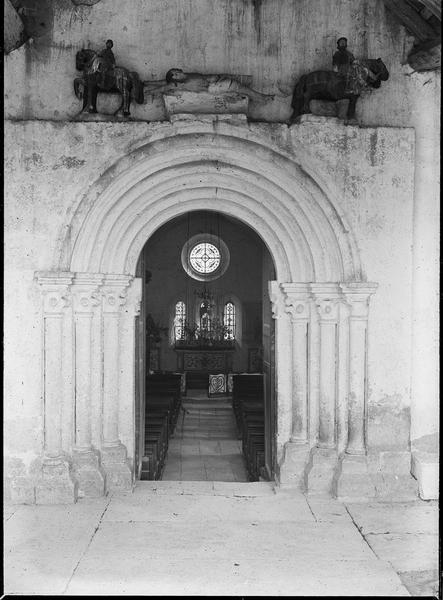 Intérieur : nef et vitraux du choeur depuis le porche fermé avec portail surmonté de sculptures représentant le marthyr de Saint-Hippolyte