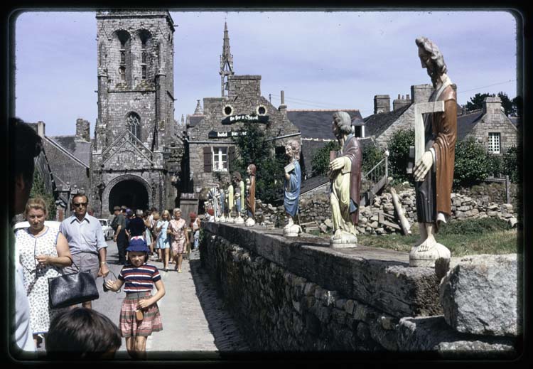 Statues exposées dans la rue ; Promeneurs ; Église à l'arrière-plan