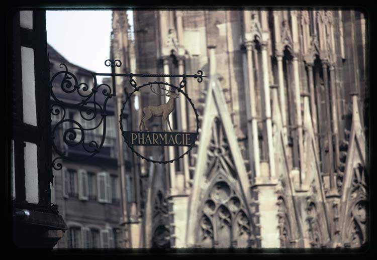 Enseigne de pharmacie ; Façade de la cathédrale à l'arrière-plan