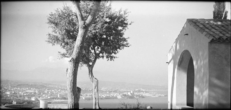 Porche ouest, vu en perspective côté sud, et vue sur Antibes en arrière-plan. Vue panoramique