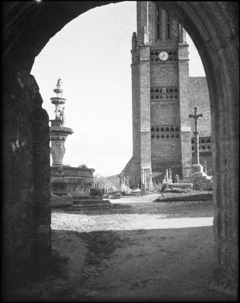 Fontaine, calvaire et base du clocher, côté sud depuis l'arc de triomphe