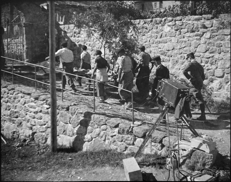 Tournage d'un film sur le chemin en pierre menant à la porte du cimetière, vue animée avec équipe technique