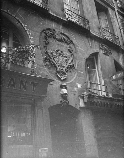 Façade sur rue avec mascaron surmontant la porte et enseigne sculptée représentant des canettes à la surface de l'eau