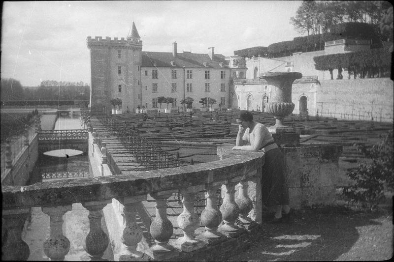 Façade sud, donjon et douves depuis le jardin d'ornement et femme appuyée contre une balustrade au premier plan