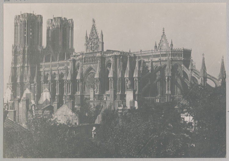 Façade sud : vue d'ensemble depuis la rue de l'Université et toiture détruite par l'incendie ; Au premier plan, les ruines du palais archiépiscopal