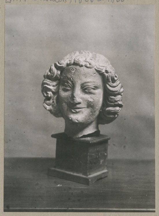 Statue : tête d'ange souriant, de face, provenant du porche nord de la façade ouest de la cathédrale