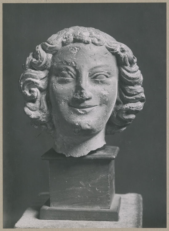 Statue : tête d'ange souriant, de face, provenant du porche nord de la façade ouest de la cathédrale