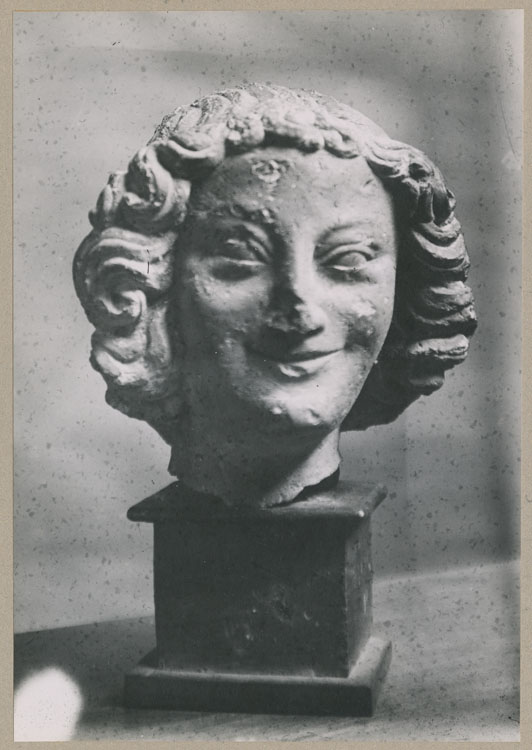 Statue : tête d'ange souriant, de face, provenant du porche nord de la façade ouest de la cathédrale