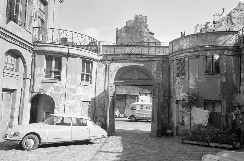 Revers de la façade avec portail ouvert depuis la cour intérieure et voiture DS stationnée