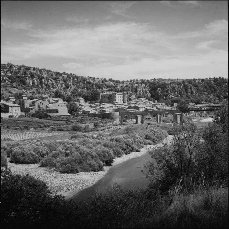 Village et château vus des rives de l’Ardèche ; viaduc ferroviaire au premier plan