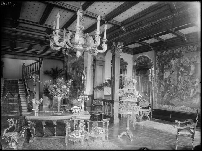 Intérieur : le hall meublé, tapisseries murales et escalier