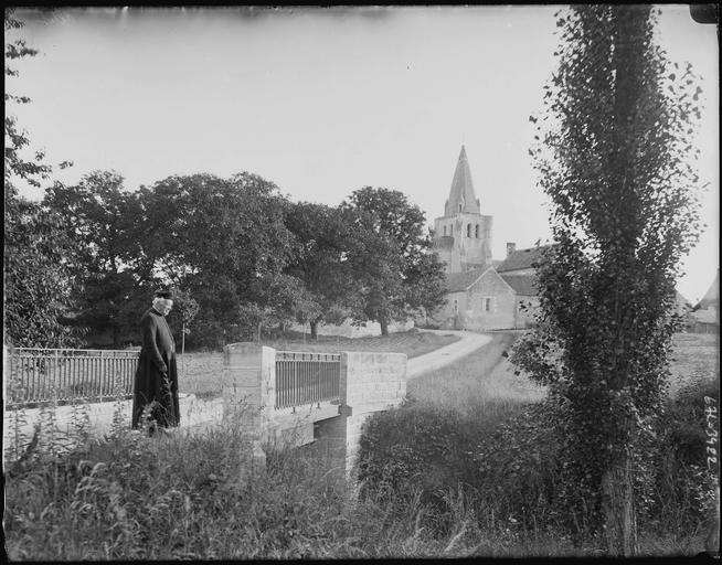 Prêtre sur un pont, église à l'arrière-plan